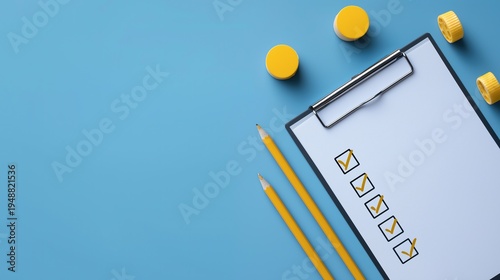 High angle view of a white clipboard with yellow check marks, pencils and small containers on a blue background, representing productivity, survey, task management and completion.
