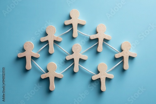 Connected Teamwork: A conceptual representation of teamwork and collaboration with small wooden figures connected by lines, forming a network of cooperation on a vibrant blue surface. 