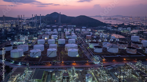 Aerial view industrial storage tank oil and gas chemical, Global fuel supply oil and gas, Industrial oil and gas storage tank farm facility energy reserve infrastructure fuel supply chain at night.