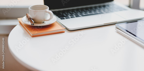 Minimal comfortable workplace with laptop computer and coffee cup on white table