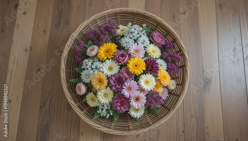 Round wicker basket with fresh flowers, colorful arrangement on wooden floor
