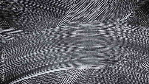 Abstract texture of white soap foam strokes on a black background. Concept of cleaning, car wash service, or hygiene. Top view of soapy suds pattern with curved lines and bubbles on dark surface.