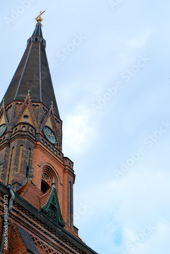 Fototapeta kuchenna Gothic church spire with cross against cloudy sky, low angle architecture view