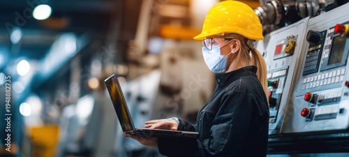 The Technician in Hard Hat Using Laptop in Modern Industrial Factory Control Room