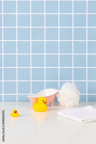 Pastel blue tile bathroom with pink bathtub white towel and yellow rubber duck