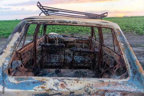 Destroyed and burnt car in the fields, accident or war concept