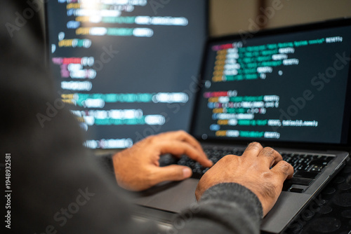 Male programmer wearing glasses works late at night with green code reflecting on his lenses focusing on software development coding and cybersecurity analysis.