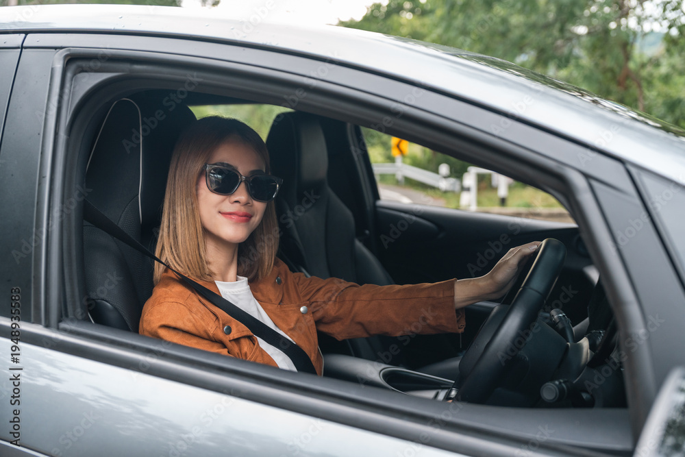 Naklejka premium Young beautiful asian women getting new car. she very happy and excited. Smiling female driving vehicle on the road on a bright day.