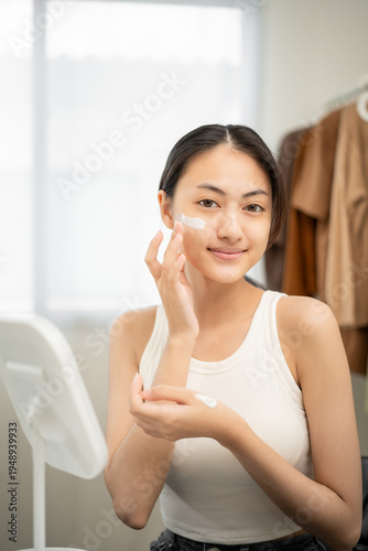 Free Download Beautiful woman applying skincare cream on smooth glowing face, smiling in mirror with confidence in routine. Apply cream to her cheeks to natural beauty, healthy skin. - GFXLoad