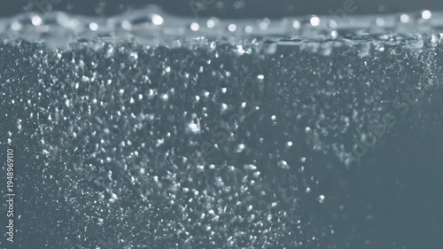 Closeup of clear water with rising bubbles and surface disturbance.