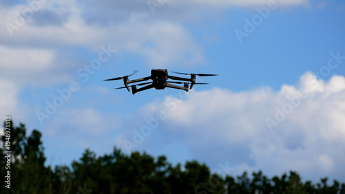 The drone hovered in the sky, flying, propellers spinning. Below you can see the forest. Reconnaissance and strike drones during the war. Ukrainian interceptor drones.