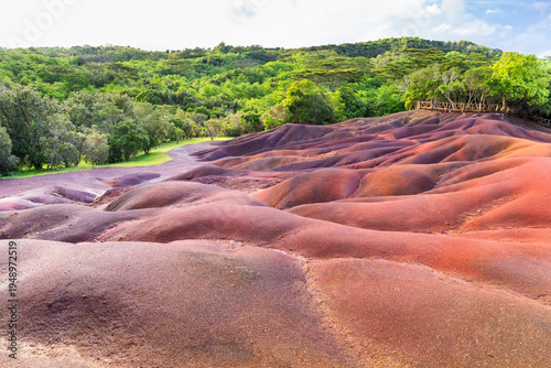 Seven Colored Earth dunes in Chamarel Mauritius with red and purple volcanic sand formations and tropical forest background.
