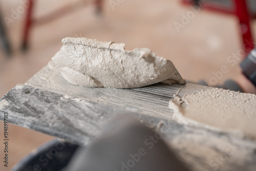 Close up of wet plaster material on metal trowel for wall finishing