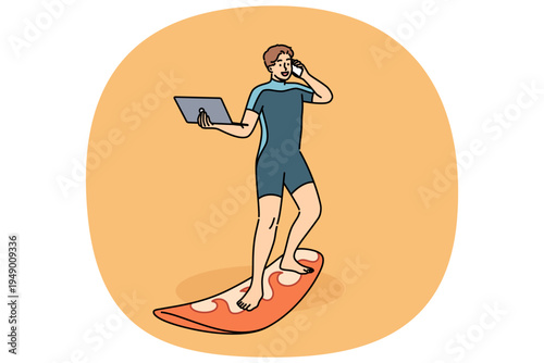 Business man works standing on surfboard, with laptop and mobile phone in hands. Happy guy in diving suit uses surfboard and freelancing gadgets at same time, working while on vacation.