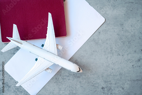 Boarding pass, plastic airplane toy, passport on a desk, top view, space for text