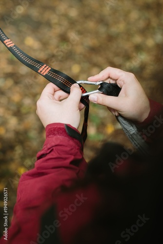 Картината върху платно Person attaching carabiner to webbing strap outdoors