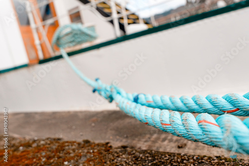 Rope tied to a boat at a dock near the water during a cloudy day