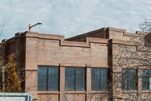 Brick building with large windows against a cloudy sky in an urban setting during daytime hours