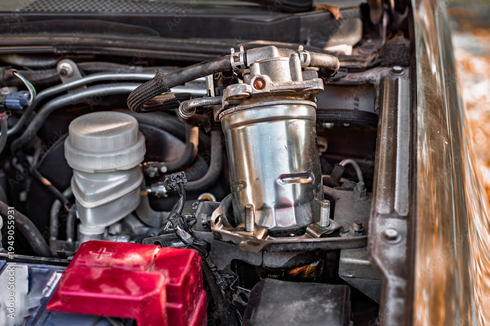 Fototapeta premium A silver fuel filter is installed in a modern car engine bay. car maintenance, vehicle repair, engine parts.