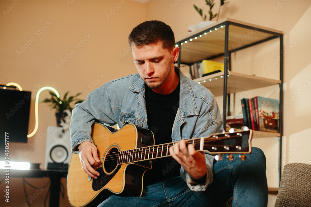 Obraz premium Young musician composing music playing acoustic guitar at home studio