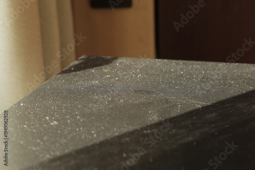Dust particles on dark surface illuminated by sunlight. Concept of household dust, cleaning, sunlight revealing dirt