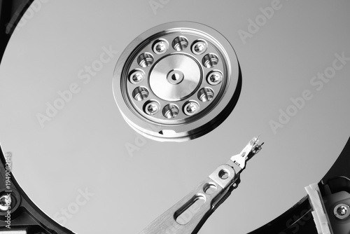 Hard disk drive interior, sleek metallic design. Read-write head hovers near spinning platter. High-tech precision, cold industrial aesthetic. Ideal for tech, innovation, or data storage themes
