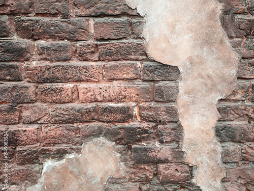 Weathered brick wall shows age and history. Chipped plaster reveals textures beneath. Rust hues add warmth to worn surface. Cracks hint at time's quiet passage. Ideal for rustic, vintage