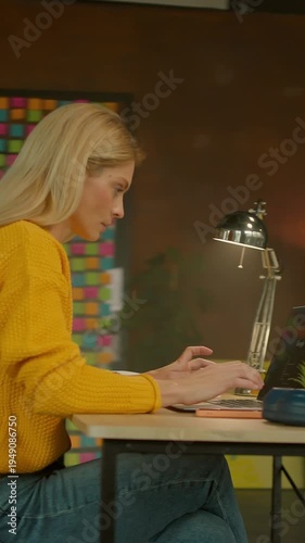 Focused woman working in industrial office setting, Casual female professional engaged in detailed note taking