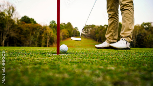 Close-Up of Golf Ball Near Hole with Golfer in Action on Course
