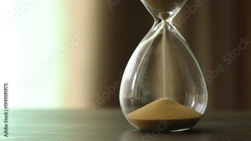 Close-up of hourglass on a wooden table with a backdrop of flowing curtains. concept of the passage of time, and the importance of time management in daily life, with copy space. 4K horizontal footage