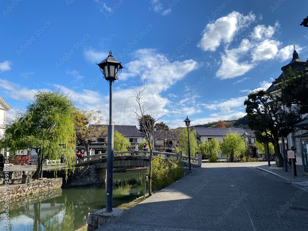 Obraz premium Kurashiki Bikan Historical Quarter with traditional white-walled buildings and willow trees along the canal, Okayama, Japan 