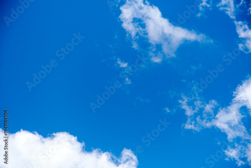 Diagonal composition of white clouds against a vibrant blue sky background