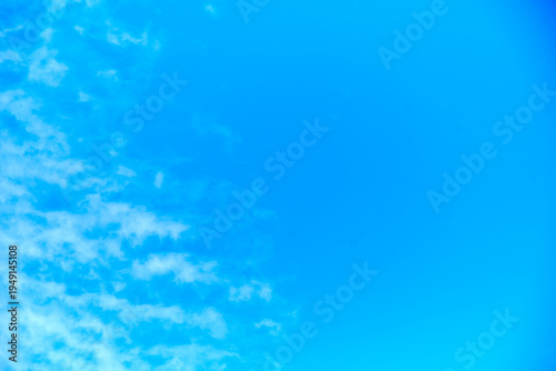 Vibrant blue sky background with textured white clouds and copy space.