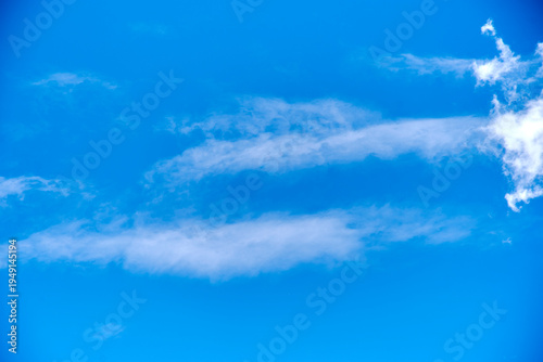 Blue sky background with elongated white clouds and copy space