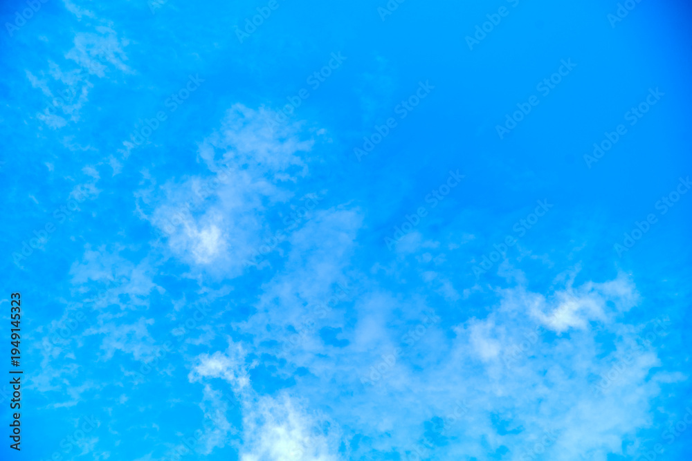 Obraz premium Blue sky background with diffuse white clouds and ample copy space.
