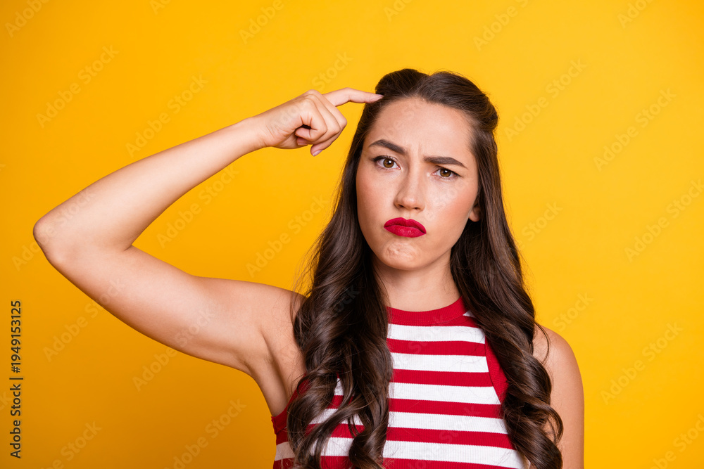 Fototapeta premium Young brunette model in striped top with puzzled expression against yellow background showcasing fashion style and lifestyle