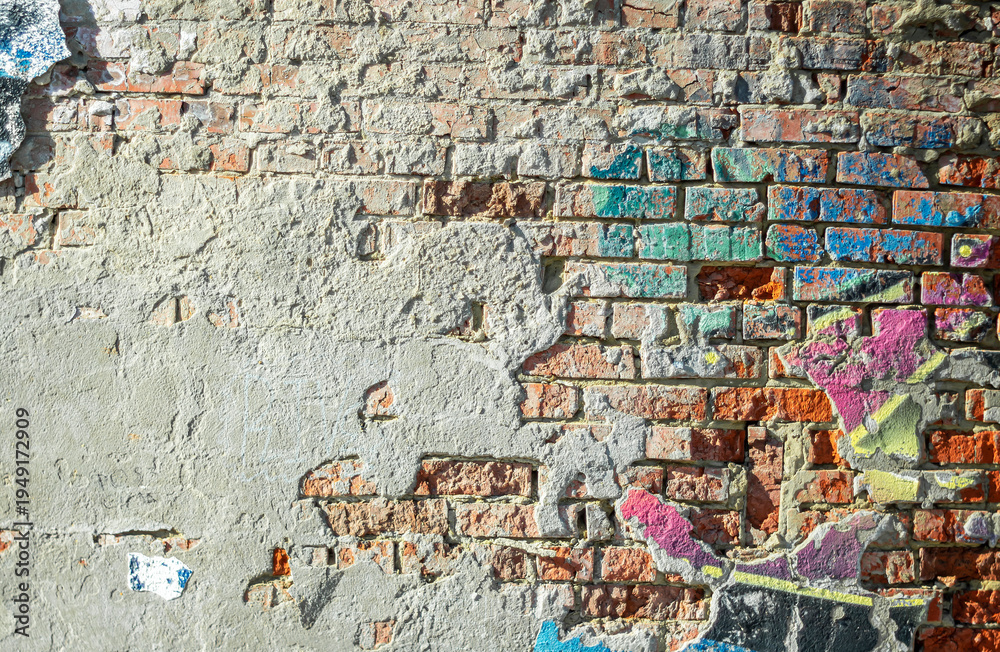 Naklejka premium Abstraction of crumbling graffiti on a city street wall. Colorful abstract background. Old, cracked, peeling paint on the wall as a background.