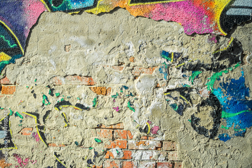 Abstract image of crumbling graffiti on a city street wall. Colorful abstract background. Old, cracked, peeling paint on the wall serves as a backdrop.