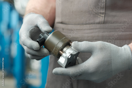 Car repair at a service station.An auto mechanic holds a new exhaust gas recirculation valve in his hands.  Visual inspection of the integrity and serviceability of the product before replacement.