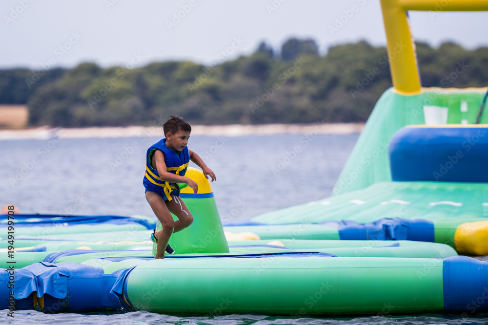 Foto Boy running on inflatable water park obstacle course
