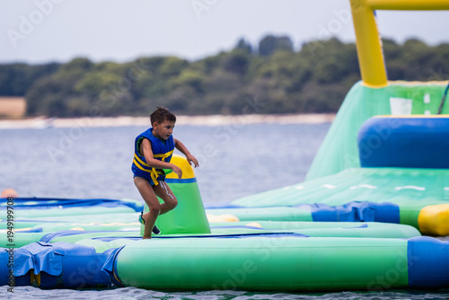 Foto Boy running on inflatable water park obstacle course