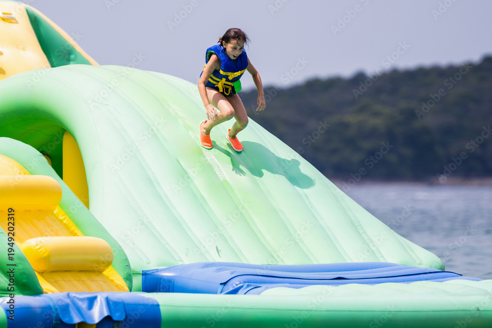 Obraz premium Girl playing on inflatable floating water park