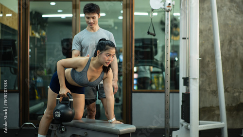 Foto A woman is performing a kettlebell row on a bench while her trainer closely chec