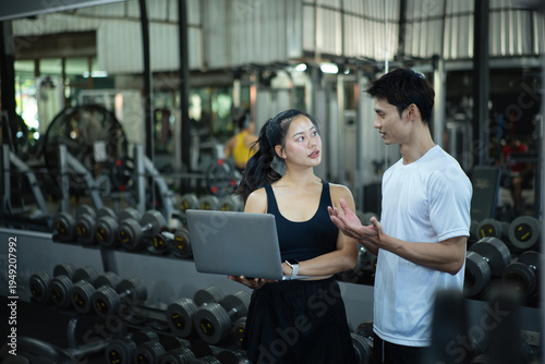 A woman trainer is discussing and reviewing physical progress with laptop