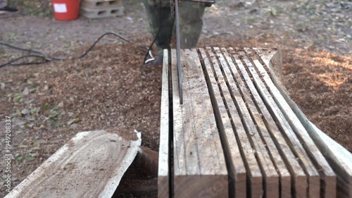 Sawing wood with a chainsaw.