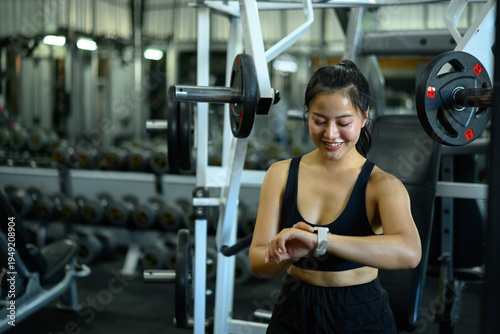 Fitness woman using smartwatch tracking data workout in gym