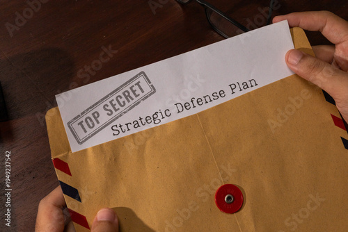Hand Presenting Strategic Defense Plan Document Emerging from Envelope With Top Secret Stamp