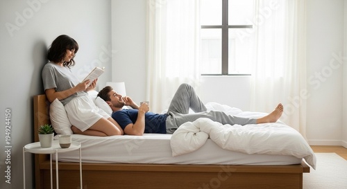 Couple relaxing in bed, reading and talking on the phone in a bright bedroom