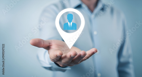 A person in a light blue shirt presents a digital location pin with a human icon in his open palm.