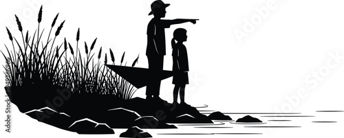 Black silhouette of a young boy in a hat pointing towards the horizon while standing with a girl on a rocky riverbank with reeds.